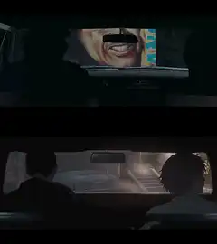 Two men in a car with a billboard
