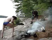 Two people fanning a campfire