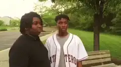 Two men standing outside, one walks away