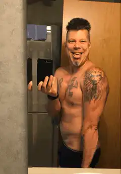 Shirtless man with tattoos taking a mirror selfie