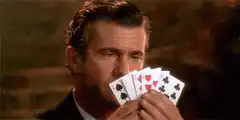 Mel Gibson holding cards then dropping them