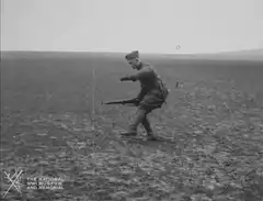WWI soldier firing rifle in field