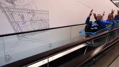 people riding shopping carts on escalator