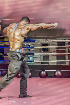 Muscular man punching in boxing ring