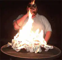 Man smoking in front of burning money