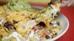 Hand pulling cheesy nacho