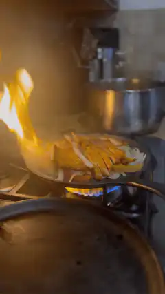 Chicken and onions flambé in a pan
