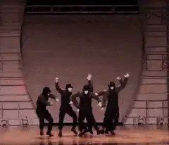 Five dancers in black ninja outfits on stage
